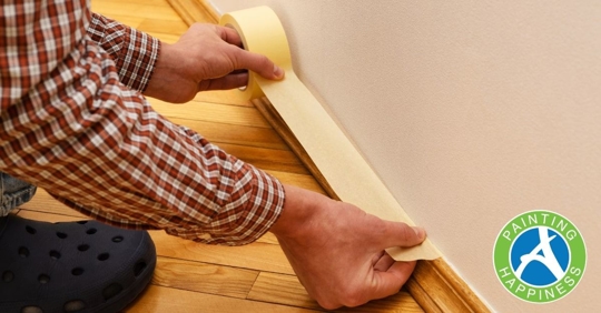 A person holding tape above wall moulding